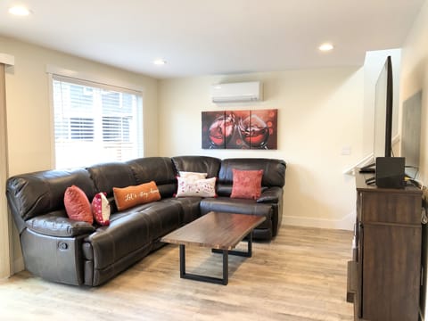 The living area features a faux fireplace, a 65" TV, and a sectional