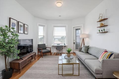 Furnished living area with smart television, adjustable desk and ample lighting.