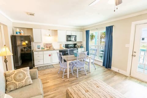 Full living room with flat screen TV. Couch, Ottoman, dining room table, and chair.