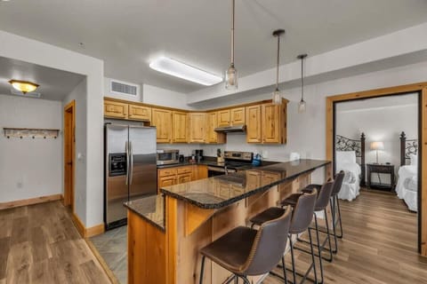 The well-laid-out kitchen boasts spacious countertops, stainless steel appliances, and a kitchen bar with four bar stools that connects the kitchen with the living room/dining area.