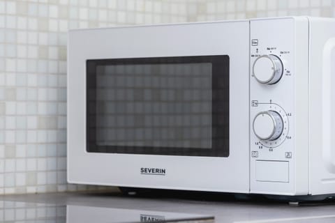 A close-up of a modern white microwave with a sleek design.
