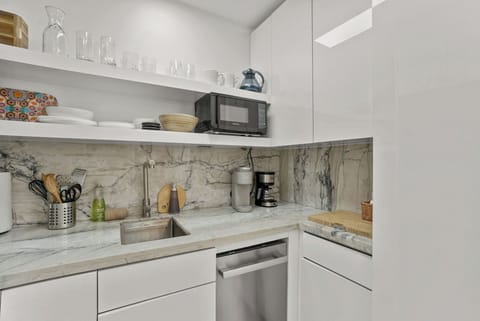 Kitchenette with microwave, mini fridge, Keurig coffee maker, glasses, plates, and cutlery
