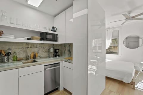 Kitchenette with microwave, mini fridge, Keurig coffee maker, glasses, plates, and cutlery
