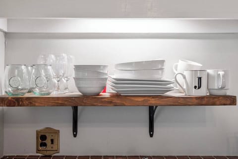Plates and cups on shelf above kitchen sink.