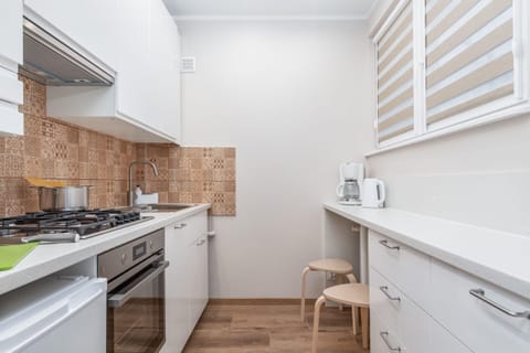 A fully equipped kitchen with wooden cabinets, modern appliances, and tiled backsplash.
