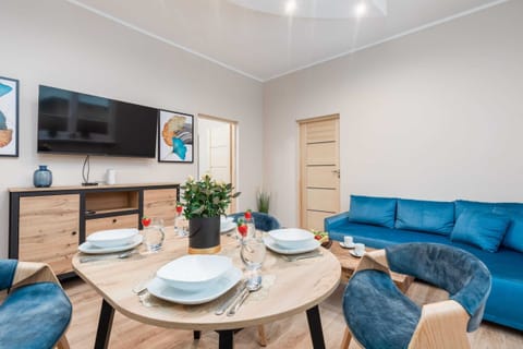 A cozy living room with a blue sofa, round coffee table, and a wall-mounted TV.
