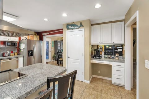 Open kitchen with granite island, appliances, and white cabinets