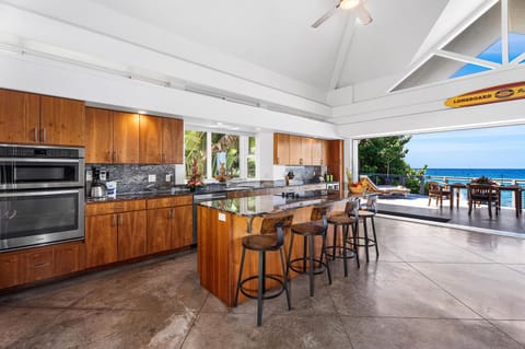 Gourmet kitchen with breakfast bar, granite counters, and ocean views—ideal for home-cooked island meals.