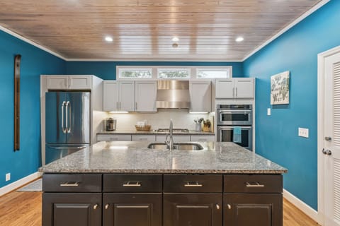 Cook your favorite meals in this stunning kitchen featuring granite countertops, stainless steel appliances, and vibrant coastal blue walls.
