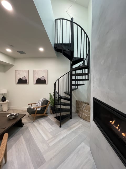 Living room with gas burning fire & spiral staircase to additional sleeping loft