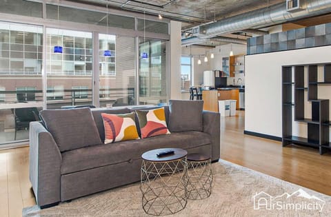 - Lounge in an airy industrial-style space featuring a comfy sofa and playful accent pillows
- Floor to ceiling windows let in bright city light while offering privacy and views
- Sleek furniture and exposed ductwork create a modern downtown vibe

