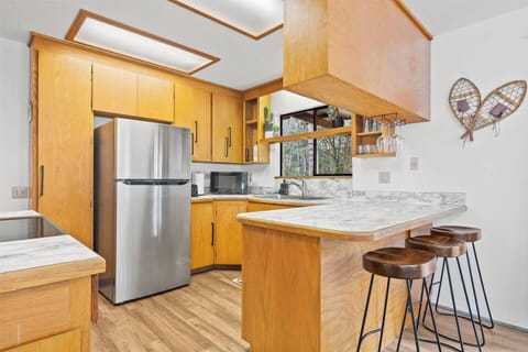 A fully stocked kitchen with all the essentials, featuring a stylish breakfast bar—perfect for morning coffee and casual meals.