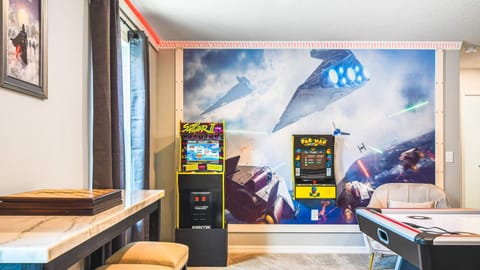 Epic game room with arcade classics and vibrant space battle mural—perfect for every gamer's retreat!