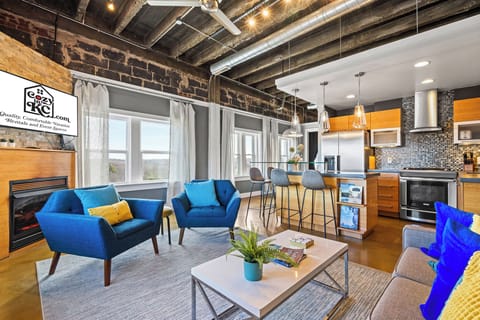 Spacious top-floor living room with exposed brick, industrial ceilings, and bold modern furnishings—an elevated retreat with loft-style character and comfort.