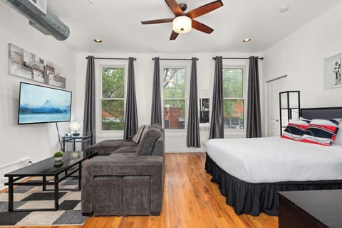 Bright top-floor corner studio with Roku TV, lounge seating, and large windows