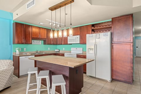 Kitchen with island and pendent lights. Fridge with water and ice dispenser.