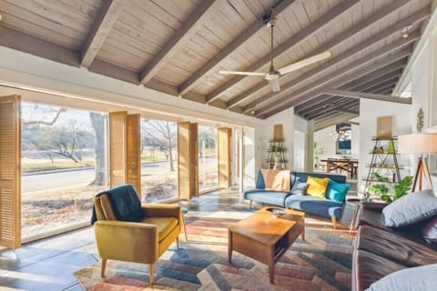 Super Cozy living Room with floor to ceiling windows, park view, exposed wood vaulted ceilings, concrete tiled floors, and mid-centruy modern decor. 