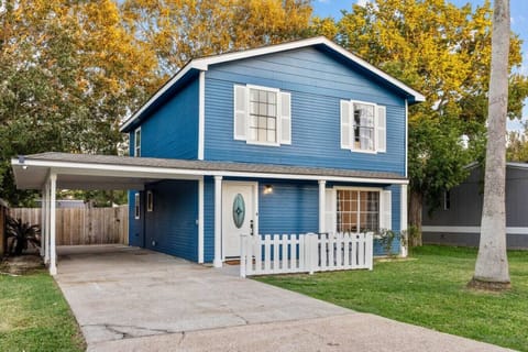Front exterior of the home with private driveway, covered carport, and charming white picket fence.