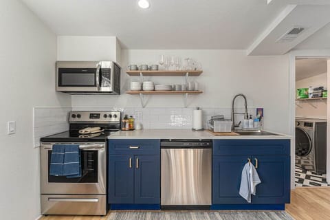 - Prepare food with ease using this fully stocked kitchen featuring sleek open shelving
- Stainless steel oven, dishwasher, and microwave offer modern cooking convenience
- Blue cabinets add bold charm to the space with subway tile backsplash detail