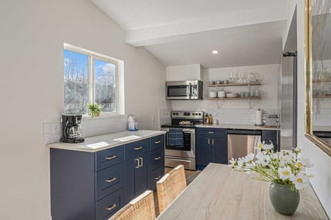 - Whip up meals in this bright kitchen with navy cabinetry and stainless steel appliances
- Enjoy natural light streaming through the window while sipping your morning coffee
- Gather around the dining table with woven chairs for cozy shared meals
