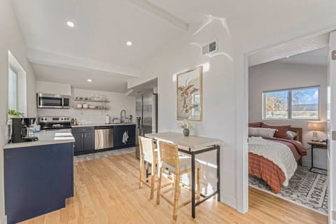 - Bright kitchen features open shelving, stainless appliances, and two seater dining nook
- Natural wood floors and white walls reflect sunlight beautifully across the space
- Thoughtful layout connects to both the bedroom and main living area