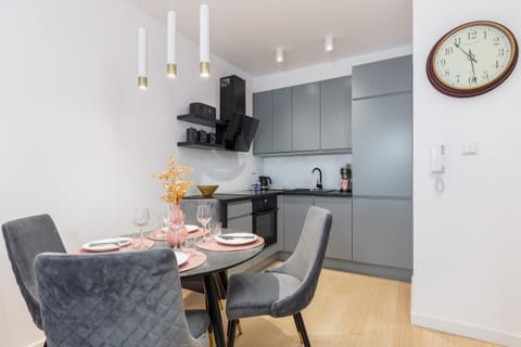 A dining area with a round table, stylish chairs, and a clock on the wall.
