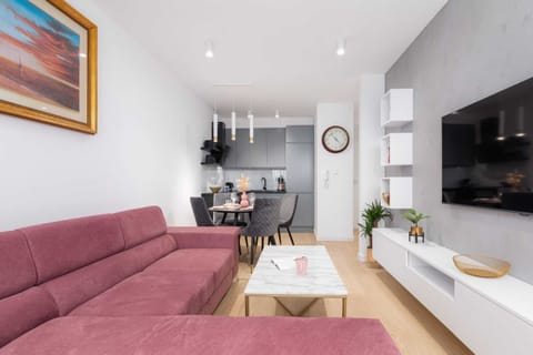 A closer look at the living room with a pink sofa and contemporary decor.
