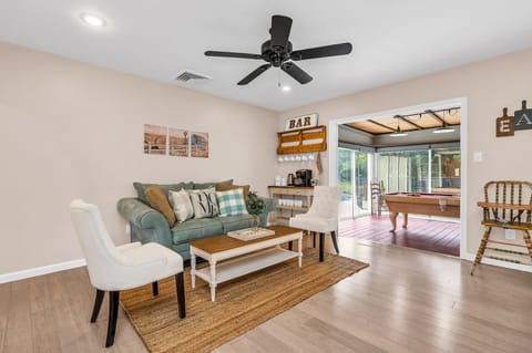 Just off the kitchen is a cozy seating area, with a light blue velvet loveseat, 2 high-backed chairs and a French-country coffee table, which sits on a natural jute rug.