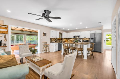 Just off the kitchen is a cozy seating area, with a light blue velvet loveseat, 2 high-backed chairs and a French-country coffee table, which sits on a natural jute rug.