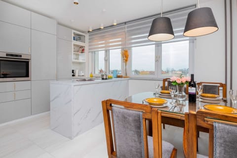 A spacious kitchen with white cabinets, a wooden dining table, and sleek gray chairs.
