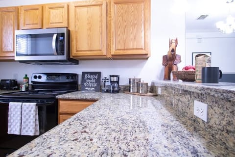 Ample granite counter space makes meal prep a breeze in this fully stocked kitchen.