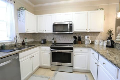 Bright, Airy, and Meticulously Clean Start your mornings right in this sun-drenched kitchen. The crisp white cabinets and neutral stone-look countertops create a refreshing atmosphere, while the large window lets in plenty of natural light.