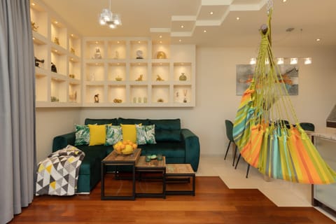 A cozy living area with a green sofa, colorful pillows, and backlit decorative shelves.
