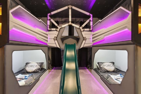 Galactic-themed kids' room with slide, twin beds, and glowing space vibes
