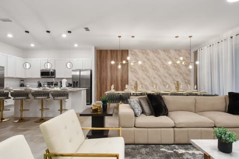 Stylish open kitchen and dining with marble accents, gold finishes, and plush seating
