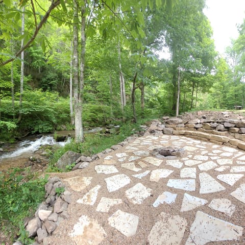 large stone fire pit with built in seats, view of the creek, steps from house