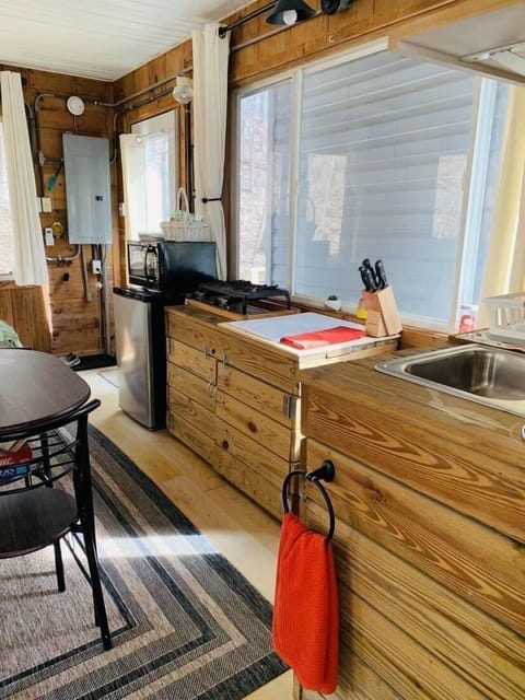 Kitchen with gas tabletop stove, fridge, microwave, coffee maker and utensils