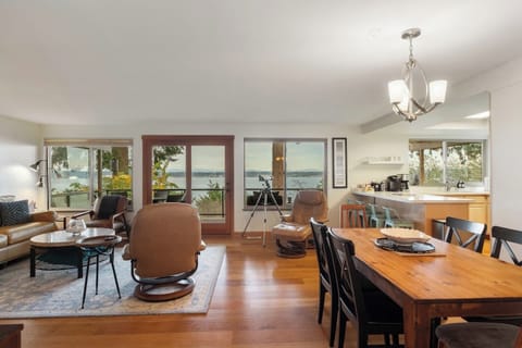 Walls of Windows with views of the water and mountains in open concept room.  Birdwatching or whale watching with Telescope.