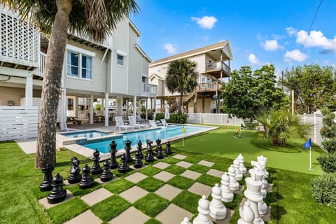 Luxury Galveston vacation rental at Mutiny Lane featuring a giant outdoor chess board, manicured lawn, and resort-style backyard perfect for family gatherings and group stays.