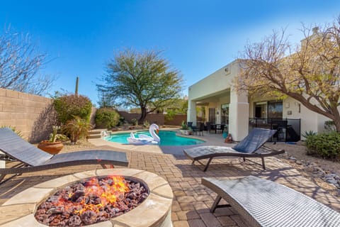 Private Backyard featuring Sparkling Blue Pool, Sun Loungers, Fire Pit, BBQ Grill, and Covered Patio with Space Heater and Lounging Areas.