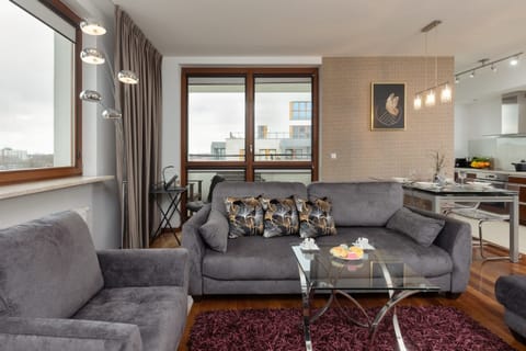 A cozy living room with a gray sofa set, coffee table, and bright windows.
