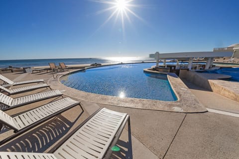 Spacious sun deck with loungers, pool, and beach views all in one.