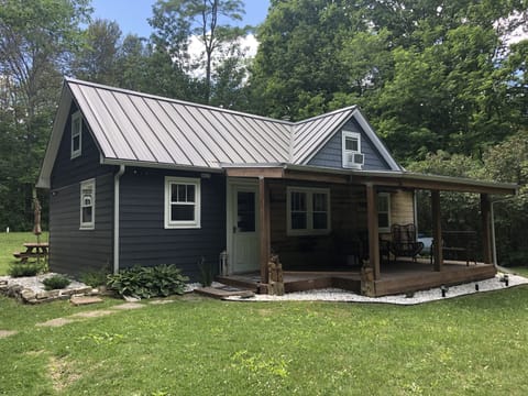 Front of the cottage. Porch has furniture, a ceiling fan, and metal roof.