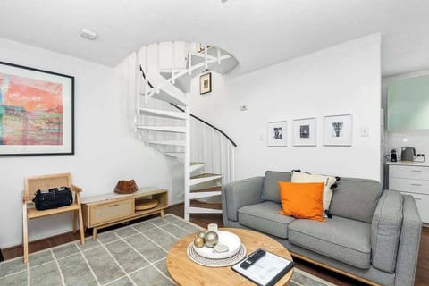 Relax in the cozy living area, featuring a comfortable sofa, a stylish rug, a convenient coffee center table, and a unique spiral staircase adding architectural interest to the space.