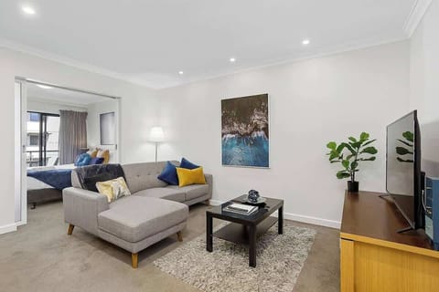 Relax in our comfy living area with a roomy sofa and large TV. A sliding door leads to the cozy bedroom, while a soft rug and warm lighting create a welcoming vibe.