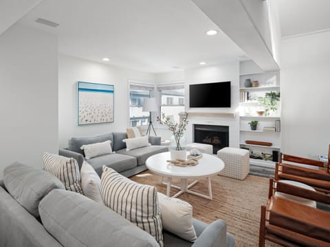 With hues of blues, whites, and natural earthy tones, along with windows that let in abundant natural light, this living room becomes a luminous and calming spot to relax.