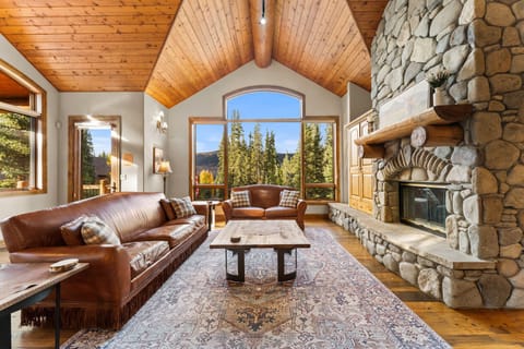 Relax by the stone fireplace with mountain views through soaring windows in this cozy living room with rich leather seating.