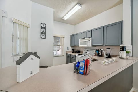 This bright kitchen boasts sleek blue cabinets and light countertops, creating a perfect meal prep space. Natural light fills the room, enhancing the organized workspace, ideal for your culinary adventures.