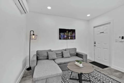 Chic, clean, and cozy—this minimalist living room offers a plush sectional, cityscape art, and modern lighting. Perfect for relaxing after beach days or urban adventures.