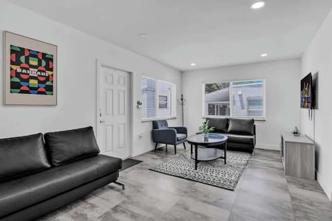 Spacious living room with sleek leather sofas, smart TV, and modern decor—perfect for relaxing after a day at the beach.